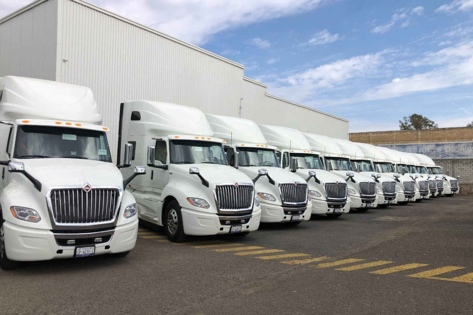 Fleet of commercial trucks parked alongside a warehouse